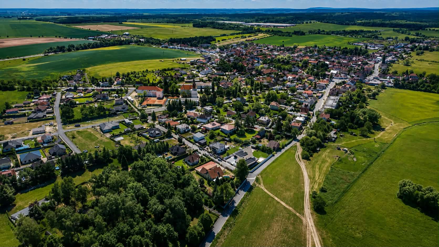 Brodce z ptačí perspektivy s lesy a poli v pozadí
